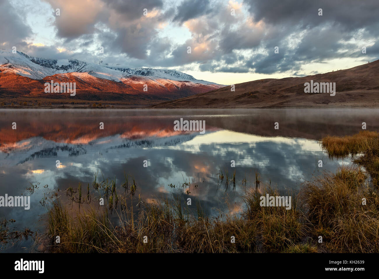 Helle malerischen herbstliche Ansicht mit einem schönen See in der Steppe, Nebel, Schnee bedeckte Berge und den Wald und deren Reflexionen auf einem Hintergrund Stockfoto