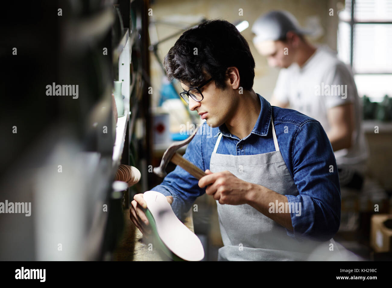 Junge Handwerker Reparatur Schuhe und Hämmern neue alleinige Stockfoto