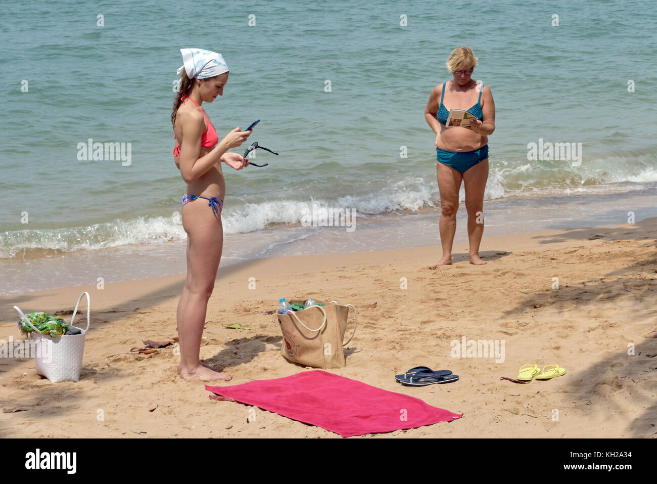 Mutter und Tochter Lesen am Strand mit alten und modernen Medien. Stockfoto