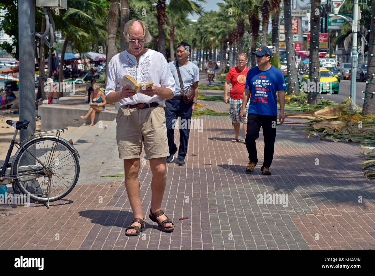 Mann liest Buch zu Fuß. . Fremdsprache lernen und lernen aus einem Buch beim Gehen. Thailand Südostasien Stockfoto