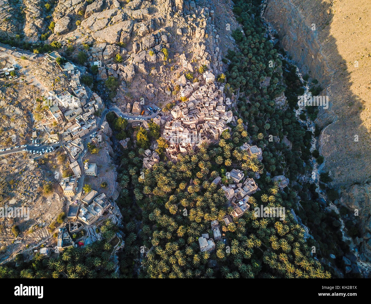 Antenne drone Ansicht einer alten traditionellen omanischen Schlamm Dorf in den Bergen unter Datum Palmen. Misfat Al Aberyeen, Oman. Stockfoto