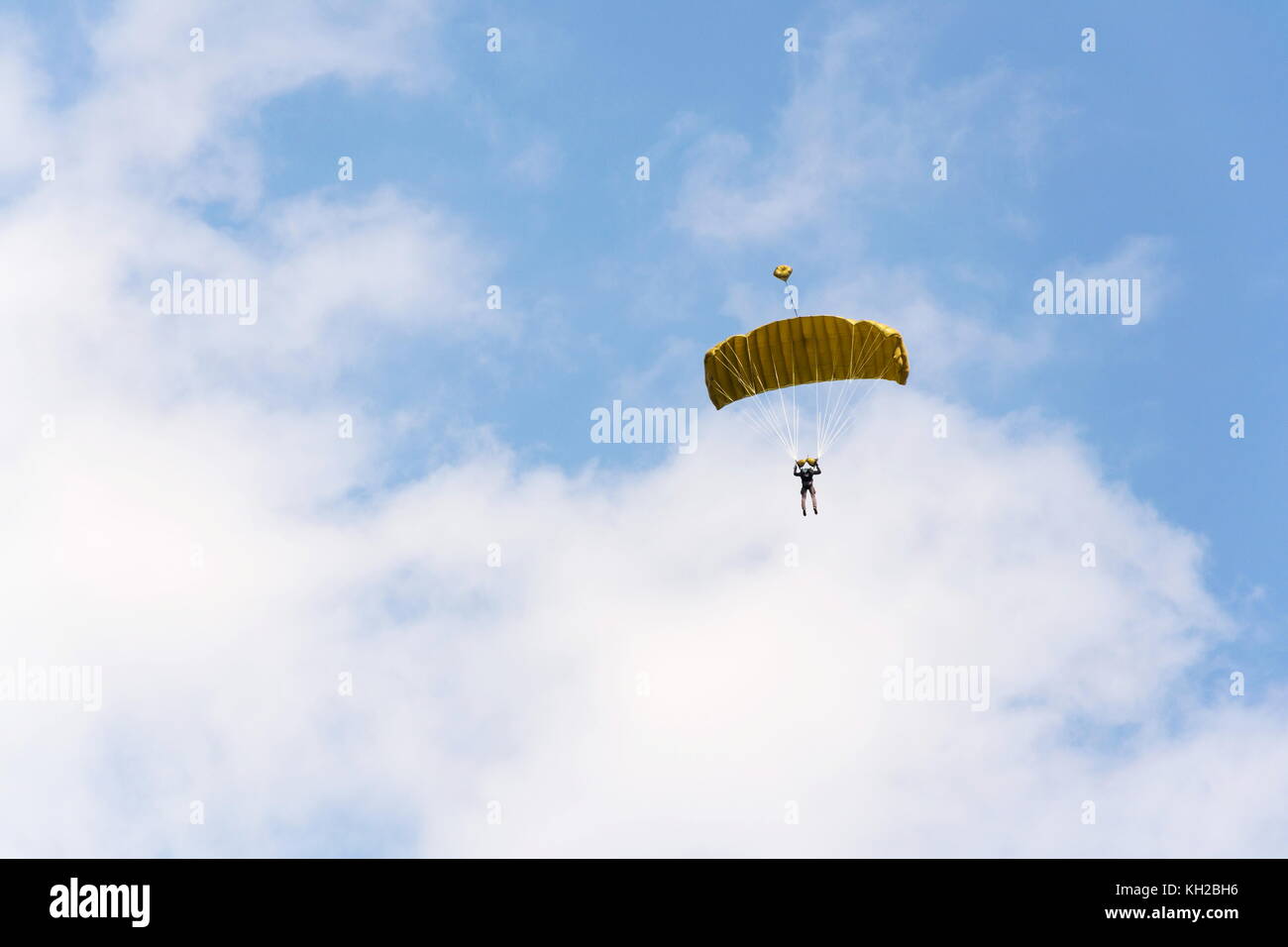 Fallschirmspringer Fallschirmspringen mit offenen gelben Fallschirm Wolken und blauer Himmel Stockfoto