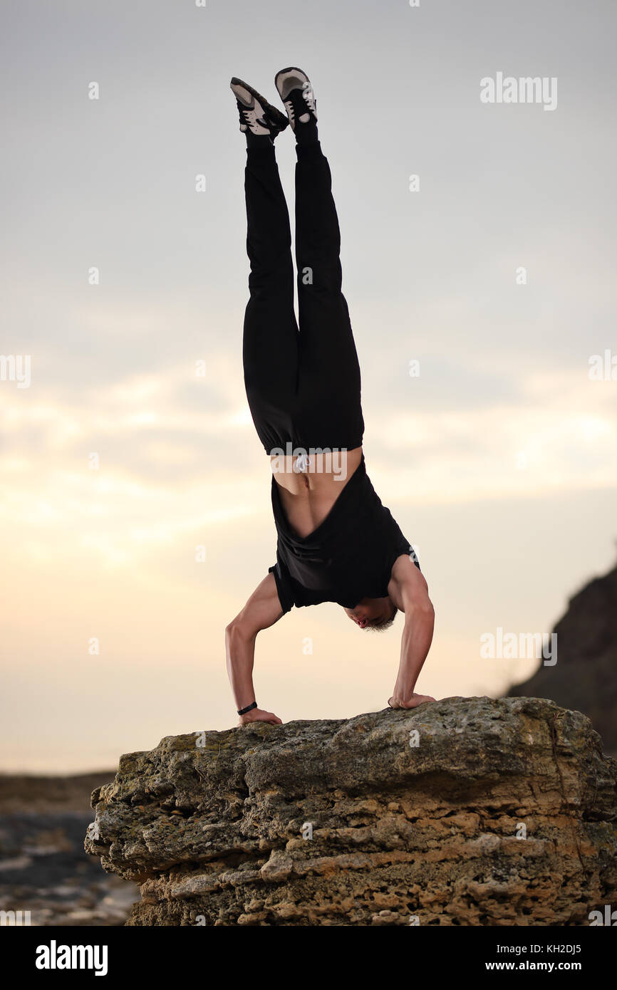 Athletischer Mann tun, Gymnastik durch die felsige Küste Küste. Stockfoto