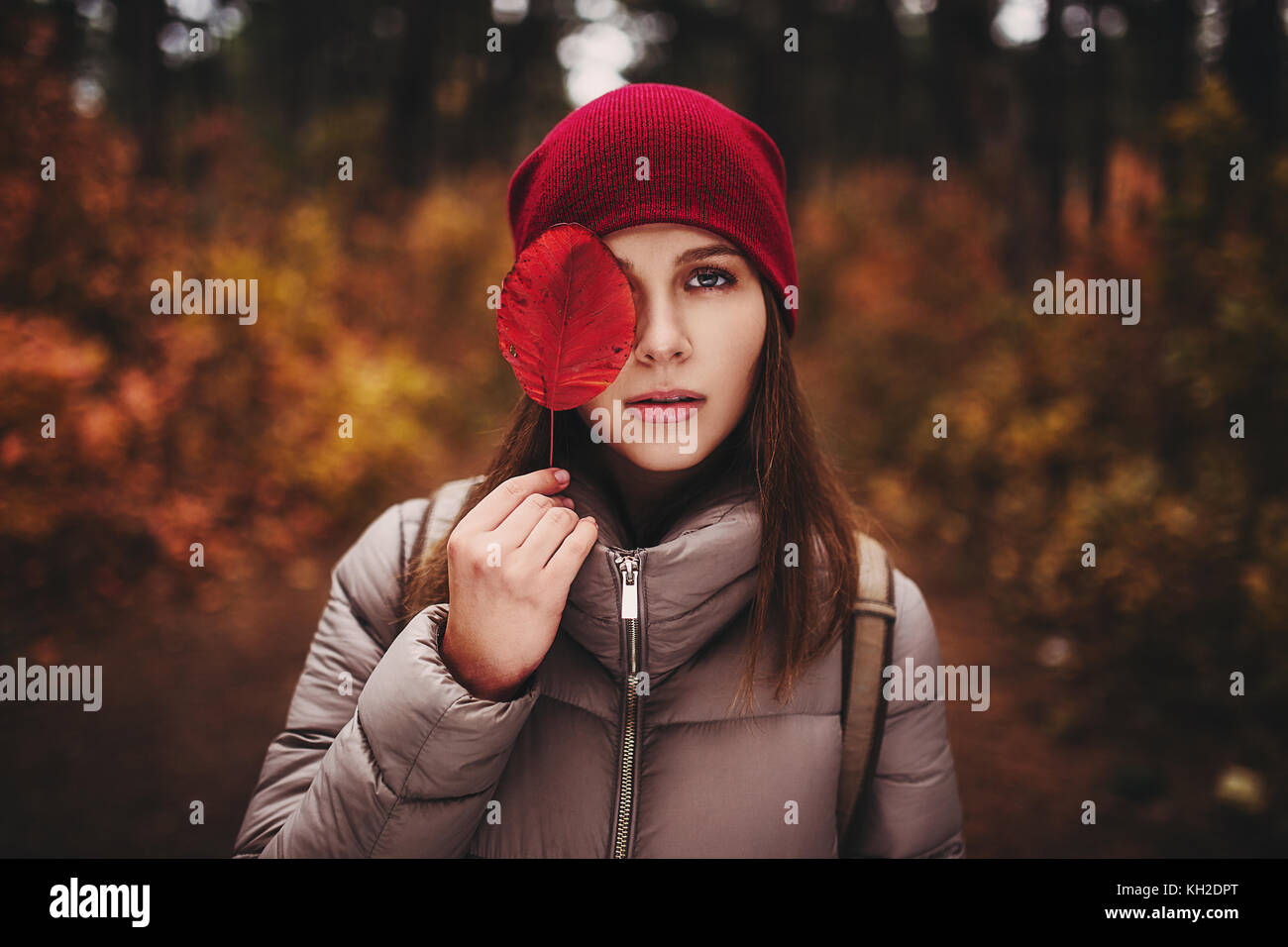 Porträt der Frau, die im Herbst Wald und deckt die Hälfte der ihr Gesicht mit Herbst Blatt. Stockfoto