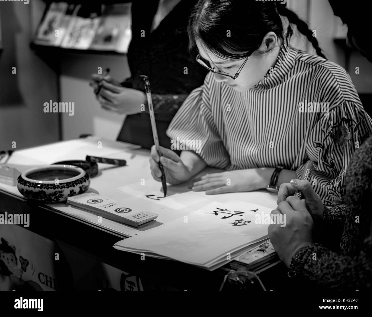 Eine schwarze und weiße horizontale Bild eines chinesischen Mädchen schreiben/zeichnen Kalligraphie im Klassenzimmer. Stockfoto