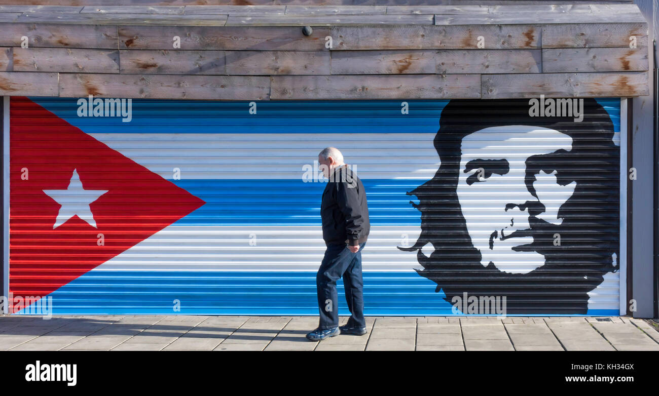 Mann, der an einer geschlossenen Bar vorbeifährt, gemalt als kubanische Flagge und Che Guerva Stockfoto