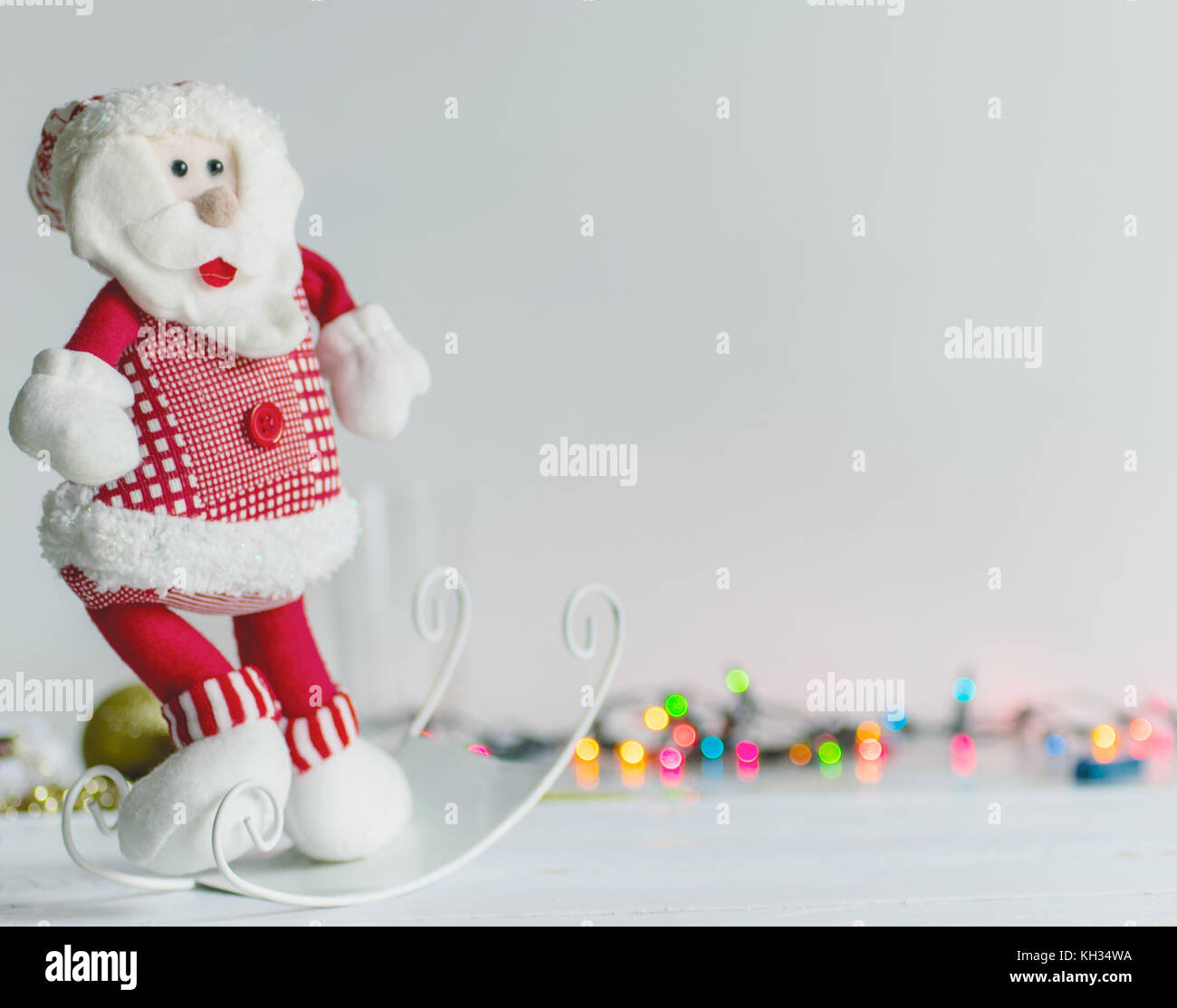 Santa Claus Dekoration Stofftier, auf weißem Hintergrund und Oberfläche, mit bunten bokeh Lichter und weihnachtliche Dekoration im Hintergrund Stockfoto