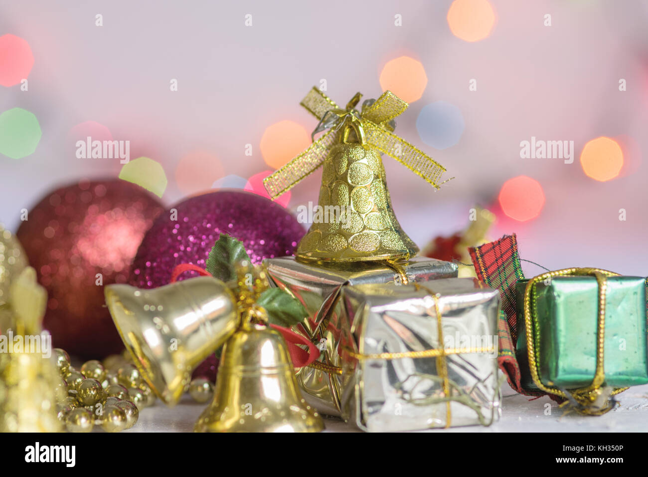 Weihnachten Dekoration, Geschenke, Ketten, Glocken und bunten reflektierenden Kugeln, auf einem weißen Holz Oberfläche und weißer Hintergrund, mit bokeh Hintergrund Stockfoto