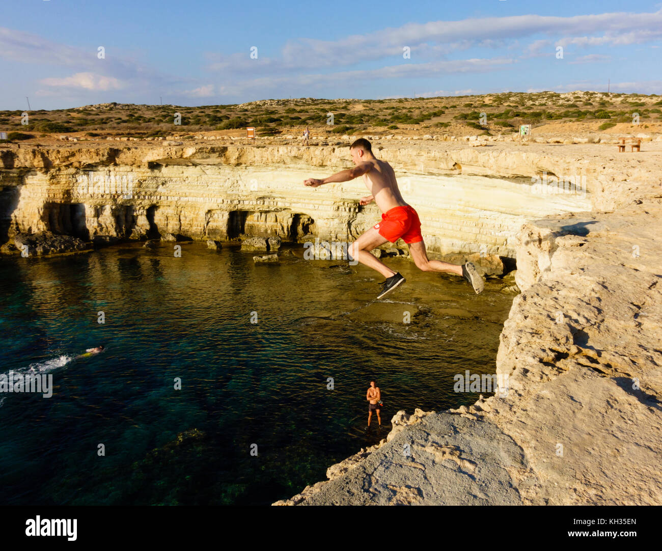 Junge männliche Tourist springt von der Klippe, Kap Greco seacaves, Zypern Stockfoto