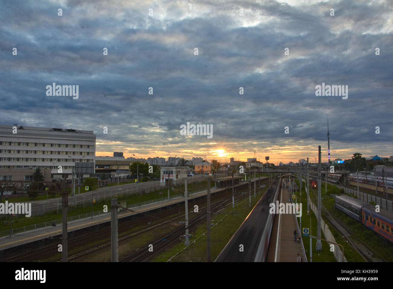 Stadtbild mit vielen Gleise und die Bewegung der Pendler Beifahrerseite elektrische Zug auf Sie. Bewegung der Wolken mit Sonnenuntergang im Hintergrund. Stockfoto