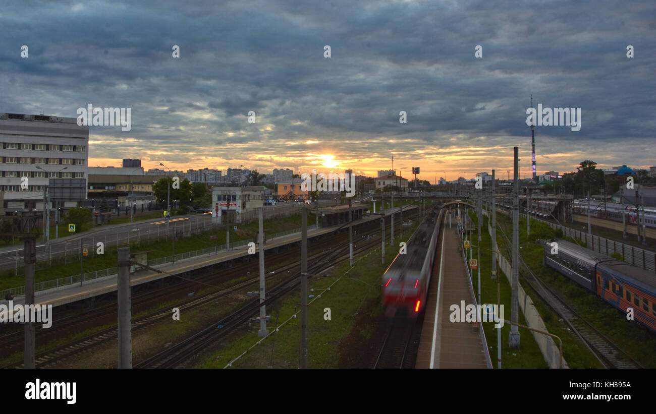 Stadtbild mit vielen Gleise und die Bewegung der Pendler Beifahrerseite elektrische Zug auf Sie. Bewegung der Wolken mit Sonnenuntergang im Hintergrund. Stockfoto