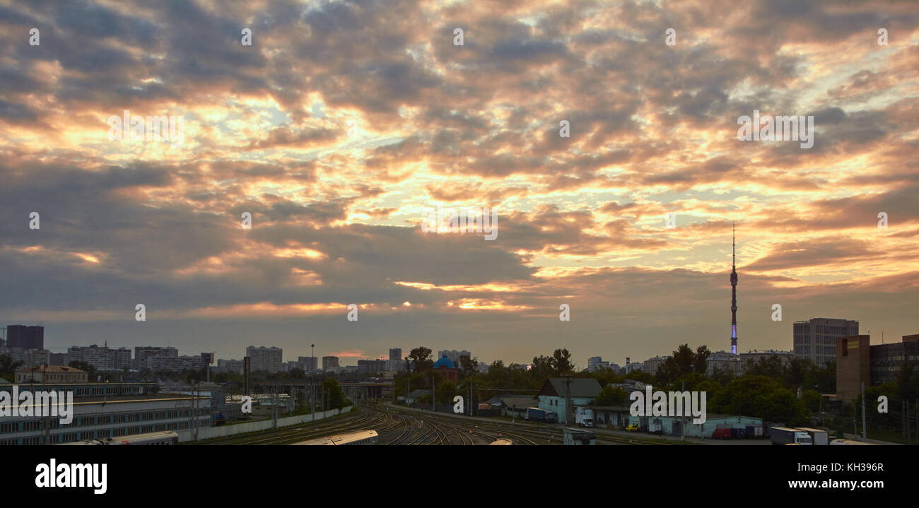 Stadtbild bei Sonnenuntergang mit den Wolken im Hintergrund und viele Gleise im Vordergrund Stockfoto