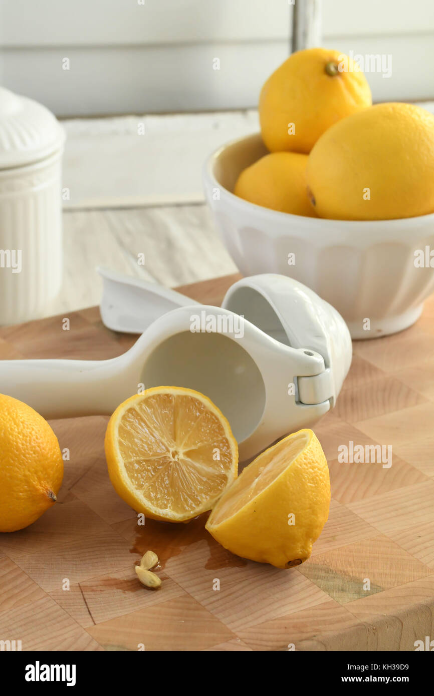 Frische organische Zitronen - in Weiß und Gelb mit Citrus hand- Saftpresse, leicht und hell auf einem hölzernen Schneidebrett - vertikale Platzierung Stockfoto