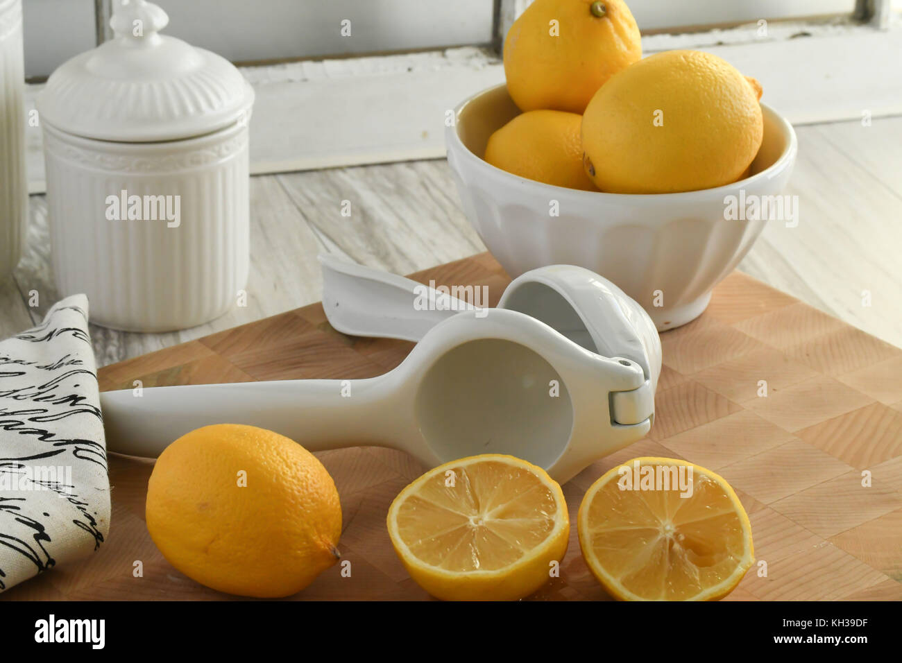 Frische organische Zitronen - in Weiß und Gelb mit Citrus hand- Saftpresse, leicht und hell auf einem hölzernen Schneidebrett Stockfoto