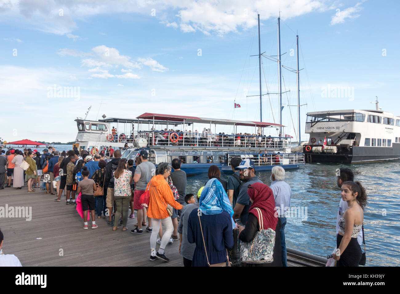 Touristen Line up an Bord Kreuzfahrt Boote an der Toronto der beliebten Hafenpromenade am Ufer des Lake Ontario Stockfoto