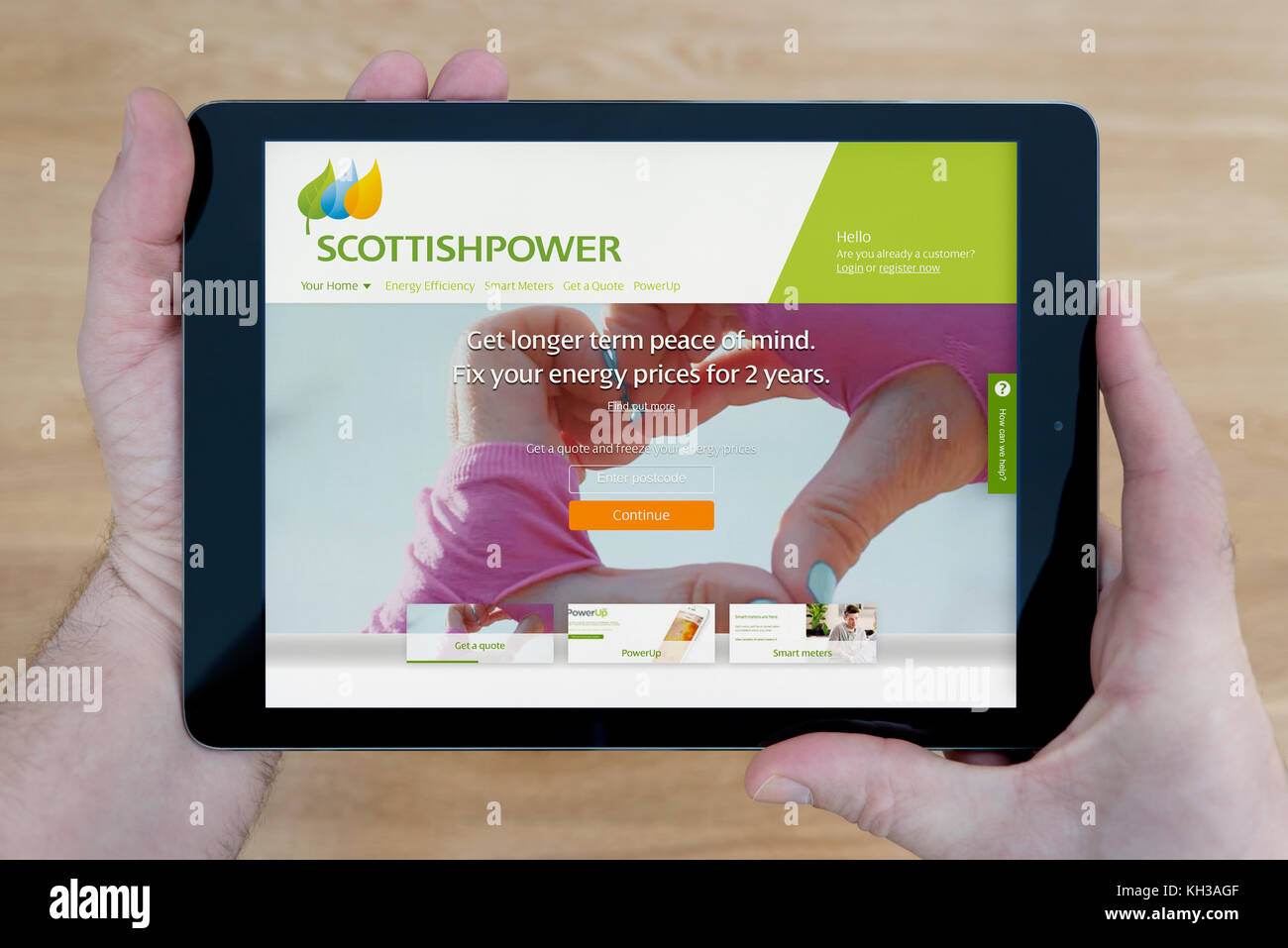 Ein Mann schaut auf die Scottish Power Website auf seinem iPad tablet device, Schuß gegen einen hölzernen Tisch top Hintergrund (nur redaktionelle Nutzung) Stockfoto
