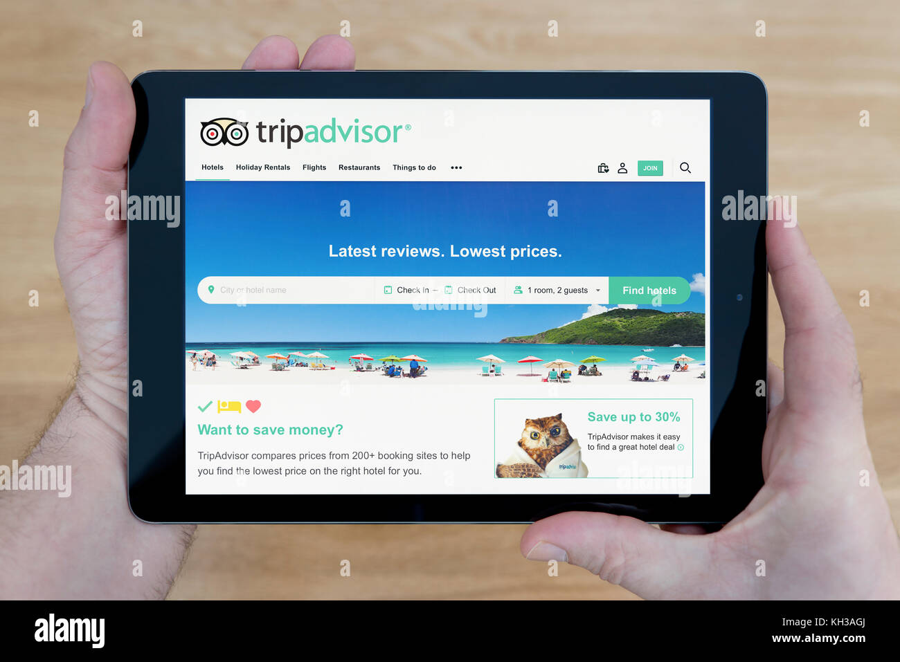Ein Mann schaut auf der Tripadvisor Website auf seinem iPad tablet device, Schuß gegen einen hölzernen Tisch top Hintergrund (nur redaktionelle Nutzung) Stockfoto