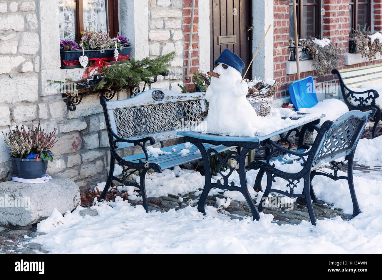 Bild einer Winterlandschaft mit einem Schneemann auf einem Gartentisch Stockfoto