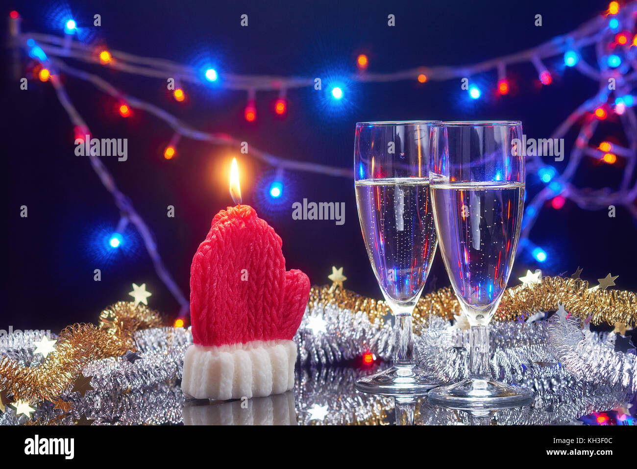 Neues Jahr Karte mit Weihnachten dekorative Kerze santa claus Handschuh und 2 Sektgläser über Girlande bokeh hellen Hintergrund Stockfoto