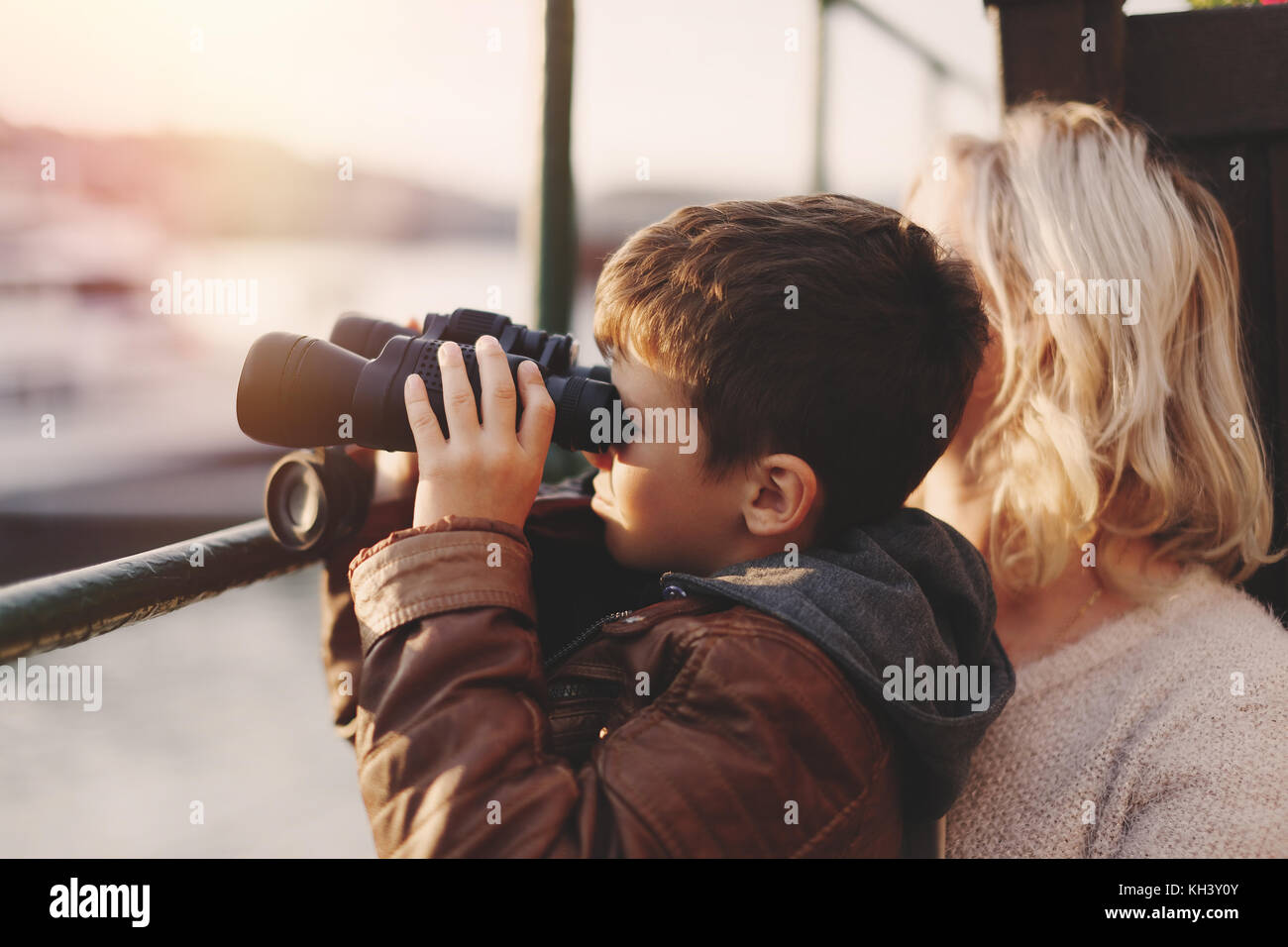 Wenig kaukasischen Jungen beobachten, Schauen, Suchen, Suchen nach Fernglas mit Mutter im Sonnenuntergang Stockfoto