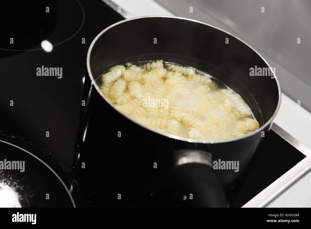 Kochendes Wasser mit Fusilli in die Steel Pan Stockfoto