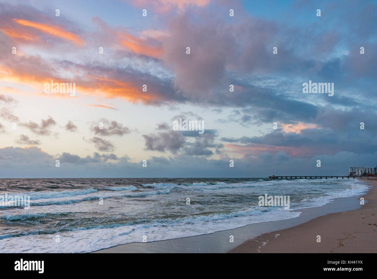 Meistens bewölkten Himmel über dem Ozean und Pier bei Sonnenaufgang Stockfoto