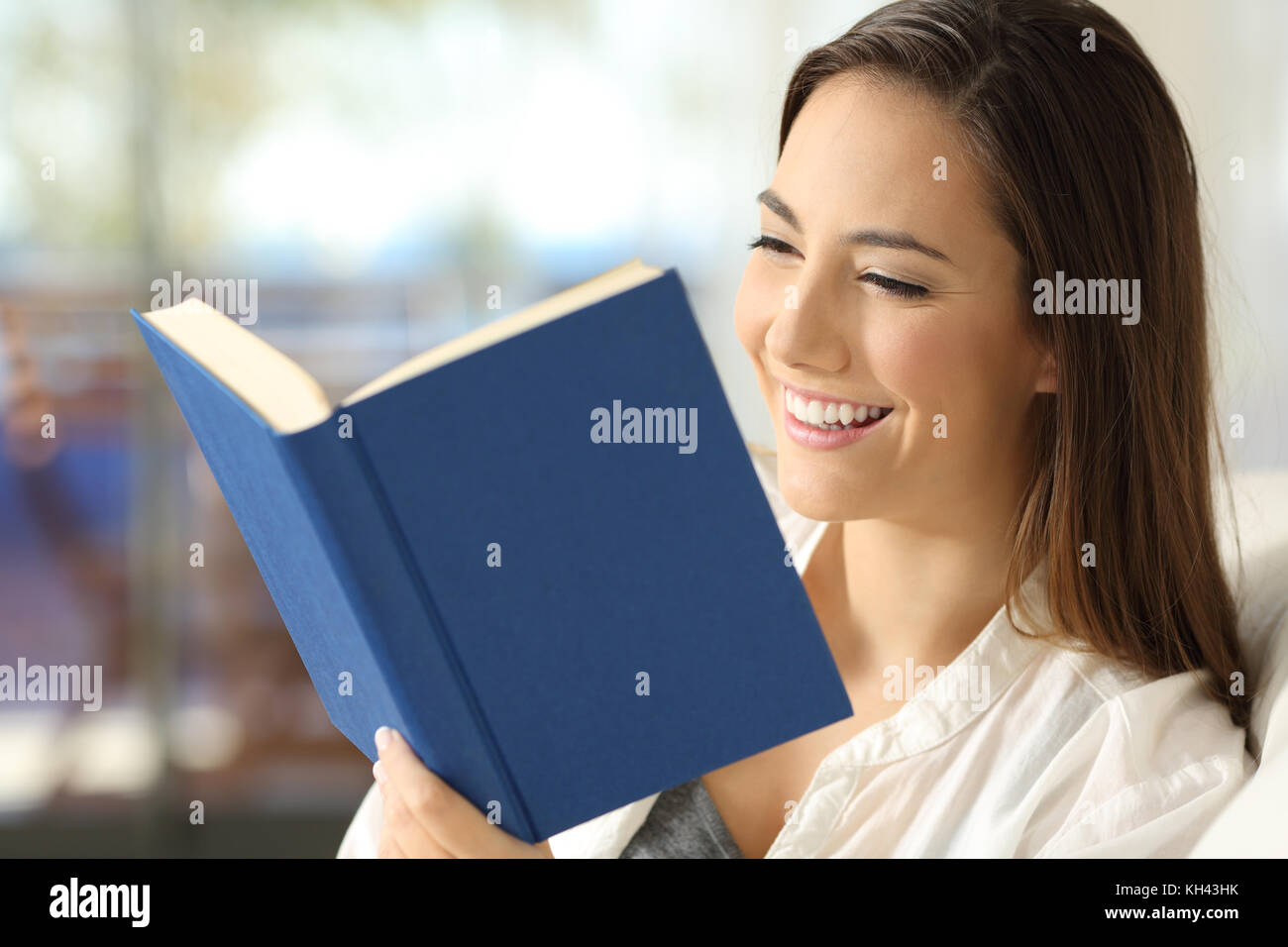 Happy Reader mit einem Buch sitzen auf einem Sofa im Wohnzimmer zu Hause Stockfoto