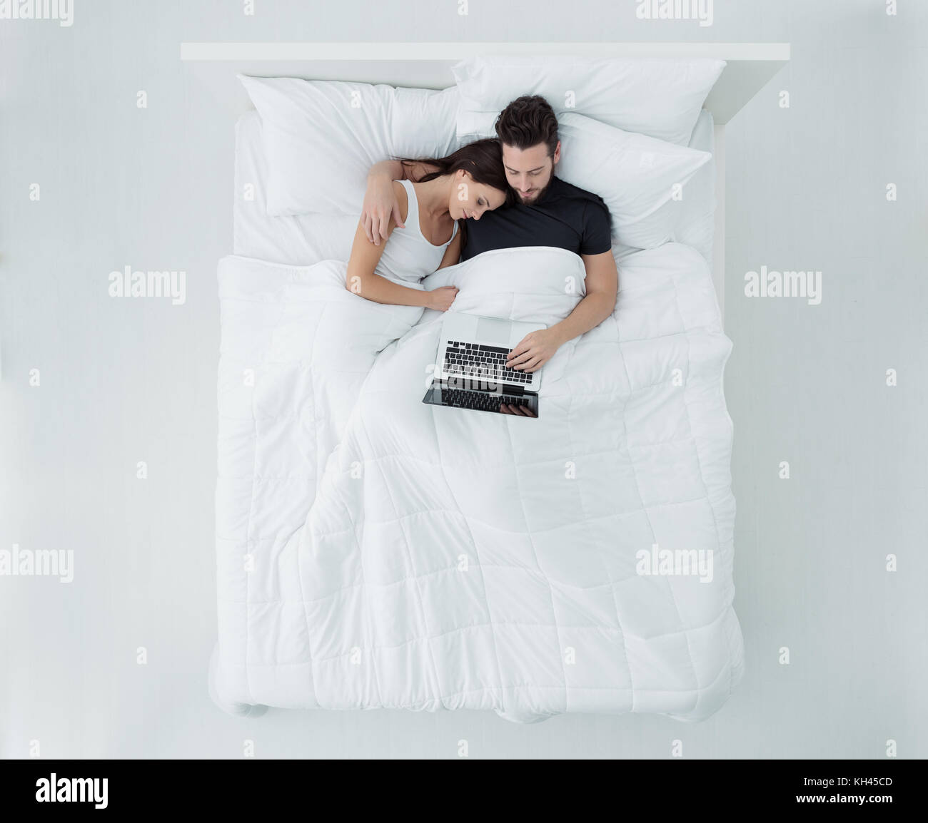 Liebespaar im Bett, sie umarmen und Verbinden mit einem Laptop, Lifestyle und Beziehungen Konzept Stockfoto
