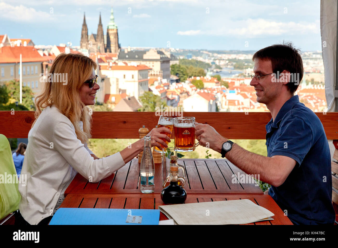 Junge touristische Paar Toasten mit Bier im Restaurant terrce Blick auf Prag, Tschechische Republik Stockfoto