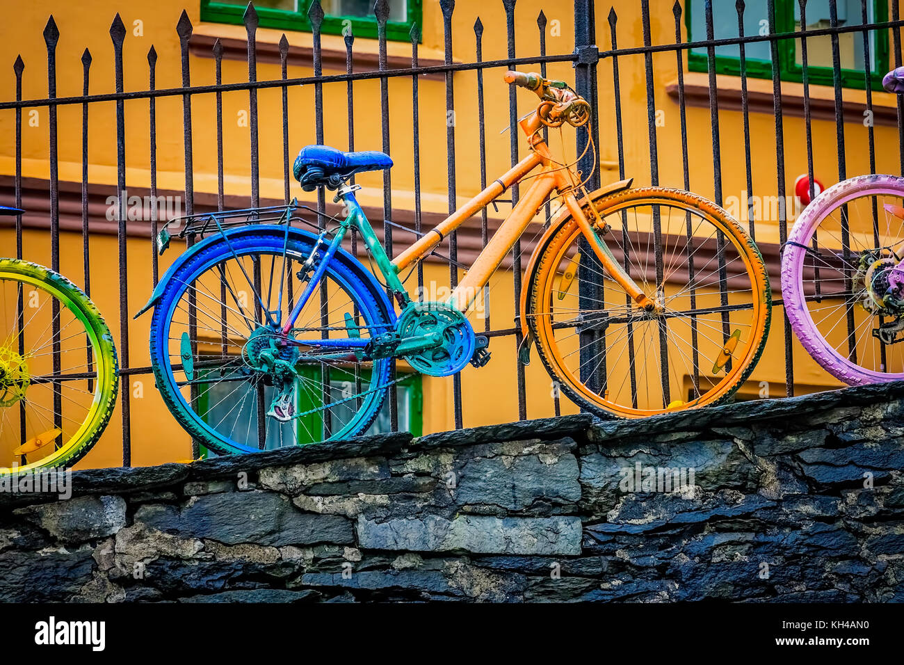 Alten rostigen alten Fahrrad und in verschiedenen Farben lackiert, gegen ein Geländer in Bergen, Norwegen schiefen Stockfoto