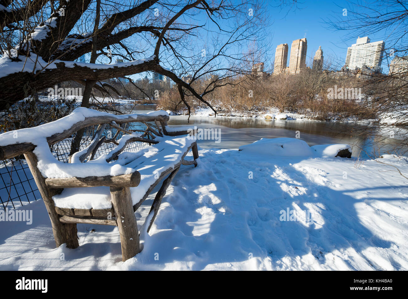 Malerische Aussicht auf die Skyline von Midtown in das Eis des zugefrorenen Central Park See spiegelt die Morgen nach einem Winter Schnee Sturm in new york city Stockfoto