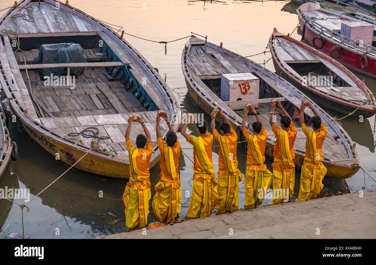 Jungen Hindu Priester bieten Wasser zu den Ganges bei Sonnenaufgang als Teil eines Rituals der Ganga Aarti Zeremonie in Varanasi Indien. Stockfoto