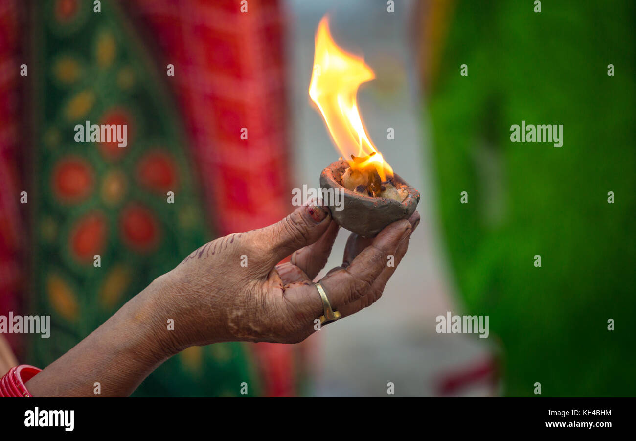 Hand eines Hindu woman holding a Ton diya Lampe als Teil eines Festes Ritual im Ganges Ghat in Varanasi Indien. Stockfoto
