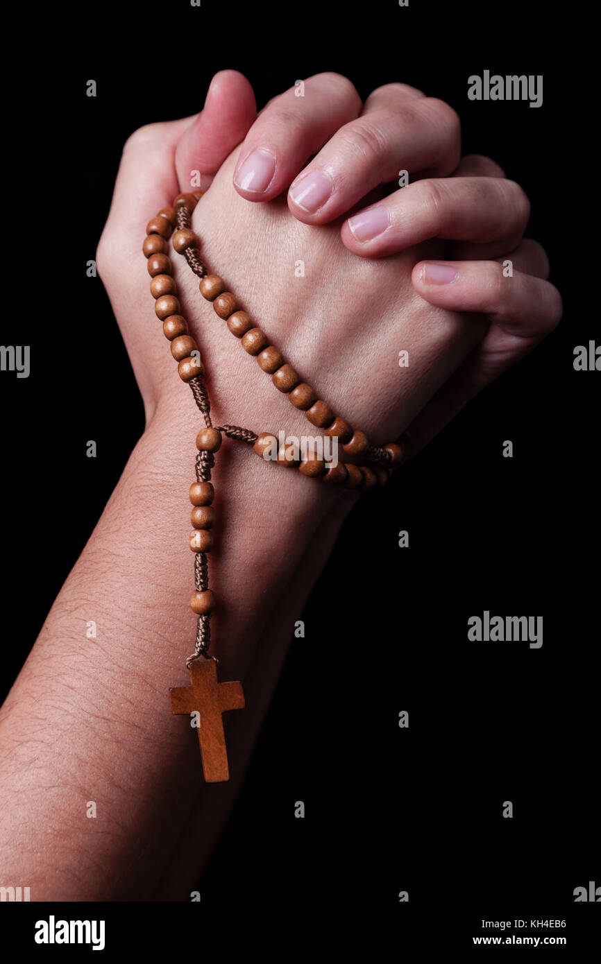 Weibliche Hände halten einen Rosenkranz beten mit Jesus Christus am Kreuz oder Kruzifix auf schwarzem Hintergrund. Frau mit christlichen katholischen Hand glauben Stockfoto