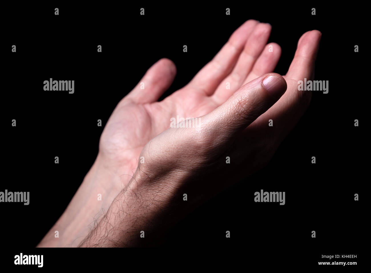 Männliche Hände betend mit Handflächen nach oben ausgestreckten Armen. schwarzer Hintergrund. Nahaufnahme der Hand. Konzept für Gebet, Glauben, Religion, religiös, Anbetung Stockfoto