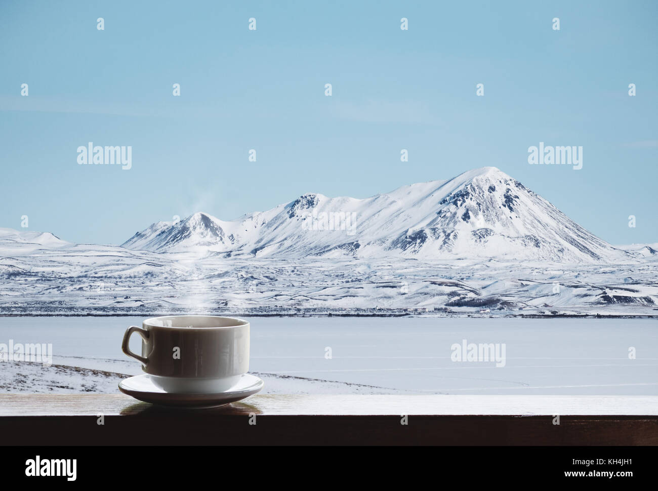 Tasse heißes Getränk mit Dampf auf hölzernen Schreibtisch und schöne Winterlandschaft Aussicht am Morgen Stockfoto