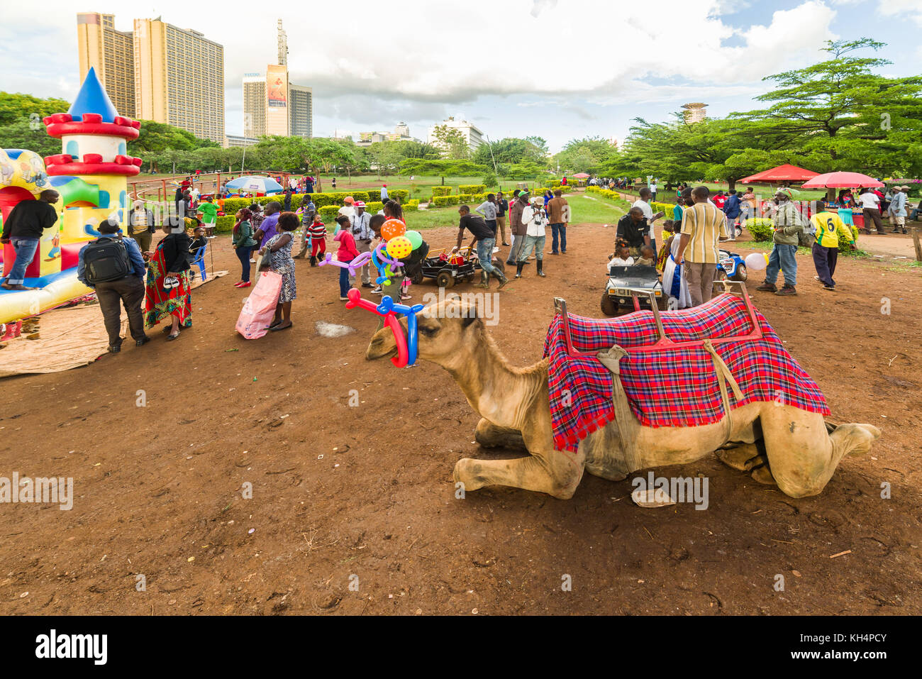 Ruhe Kamel im Vordergrund der Messe mit Fahrten der Kinder im Uhuru Park, Nairobi, Kenia Stockfoto