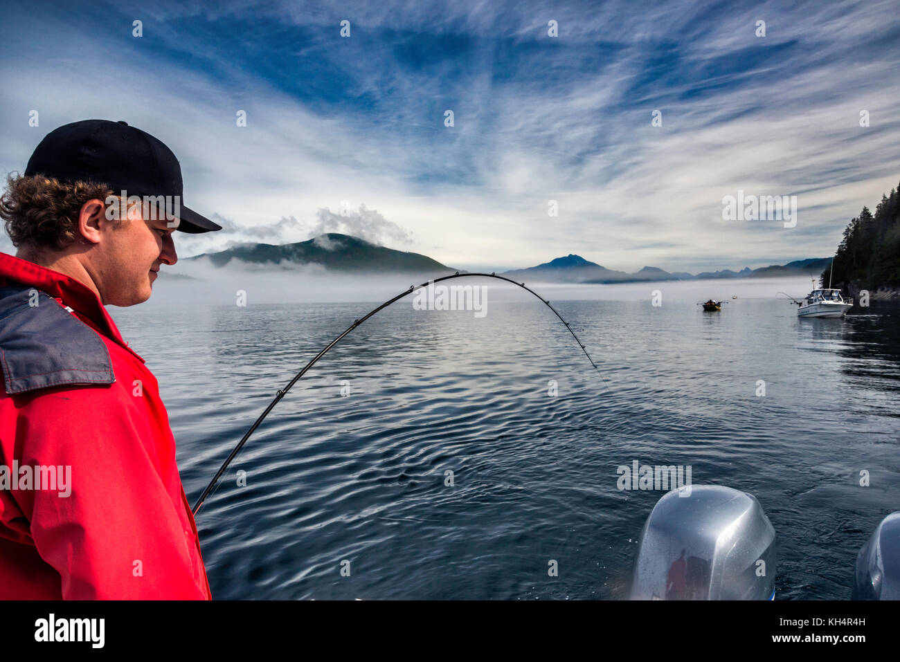 Junger Mann mit Angelrute auf dem Boot, nebeliger Tag in der Johnstone Strait vor Vancouver Island, British Columbia, Kanada Stockfoto