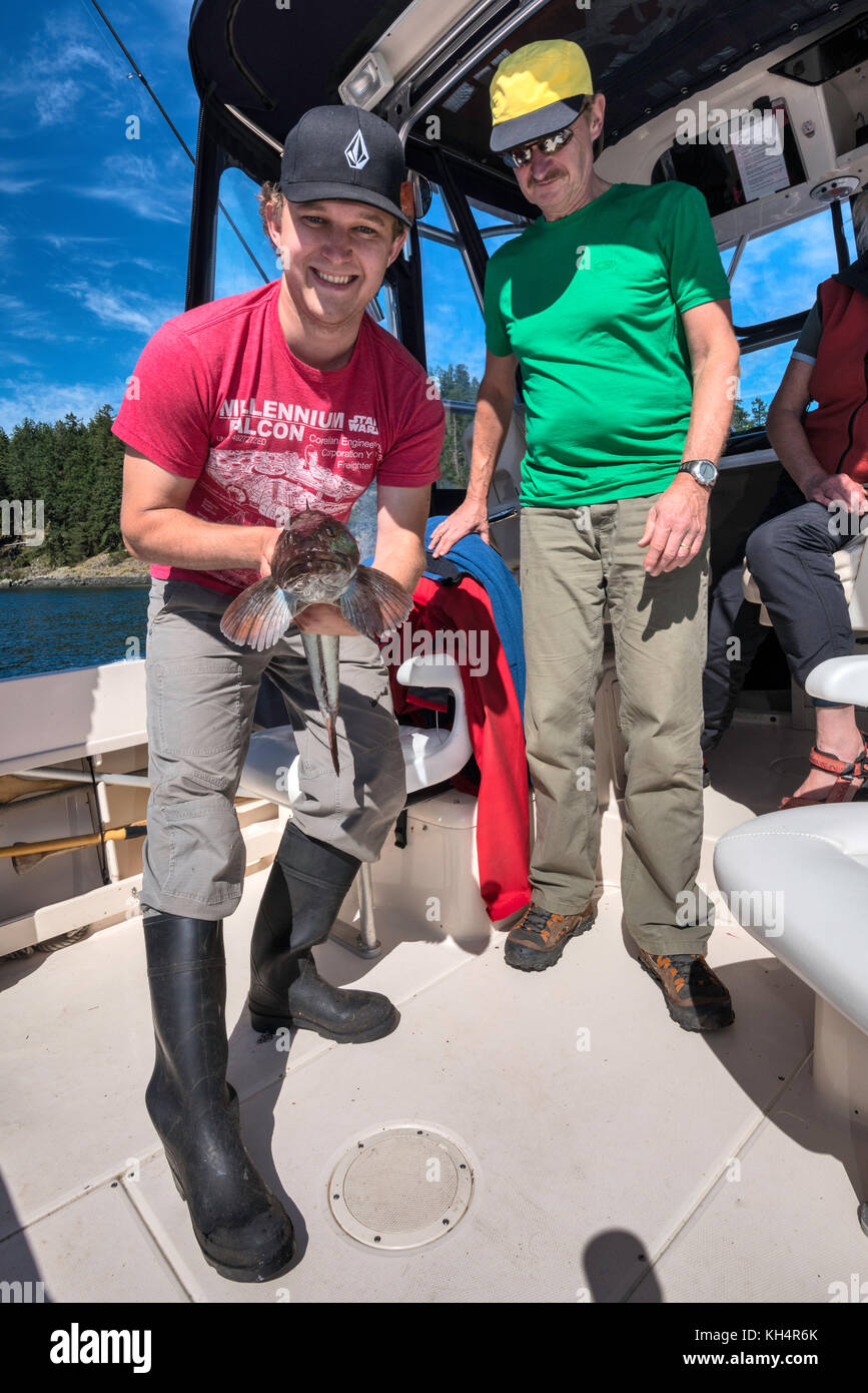 Zwei Männer, Vater und Sohn, mit gefangenem Fisch, Lingcod, auf dem Boot in Vancouver Island, British Columbia, Kanada Stockfoto