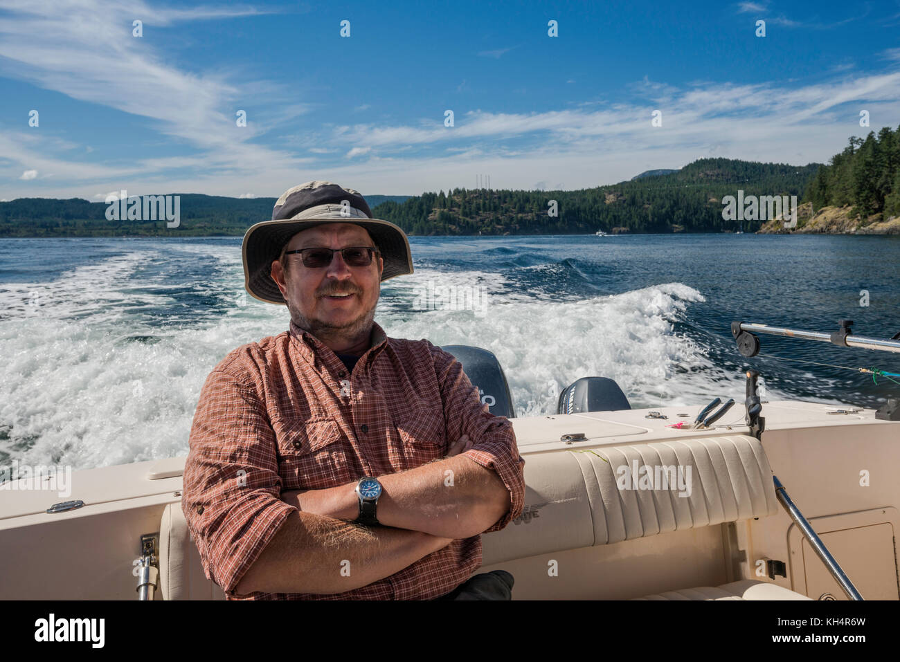 Mann mittleren Alters, der in einem Schnellboot sitzt und von einem Angelausflug zurückkehrt, in der Johnstone Strait vor Vancouver Island, British Columbia, Kanada Stockfoto