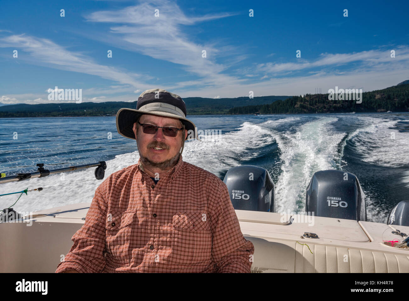 Mann mittleren Alters, der in einem Schnellboot sitzt und von einem Angelausflug zurückkehrt, in der Johnstone Strait vor Vancouver Island, British Columbia, Kanada Stockfoto