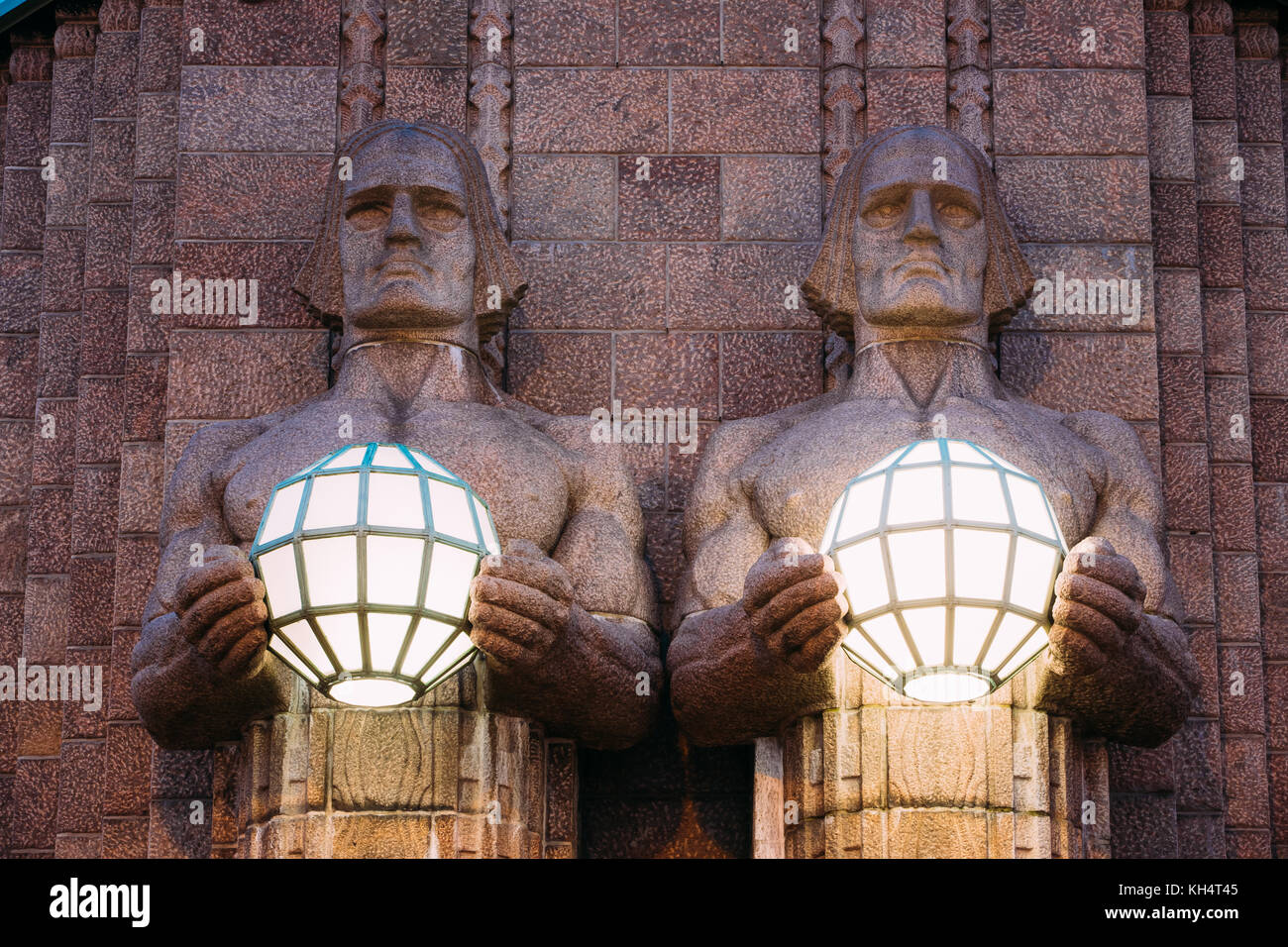 Helsinki, Finnland. Nacht Blick auf zwei Paare von Statuen, die die kugelförmige Lampen auf Eingang Hauptbahnhof Helsinki. Abend oder Nacht il Stockfoto