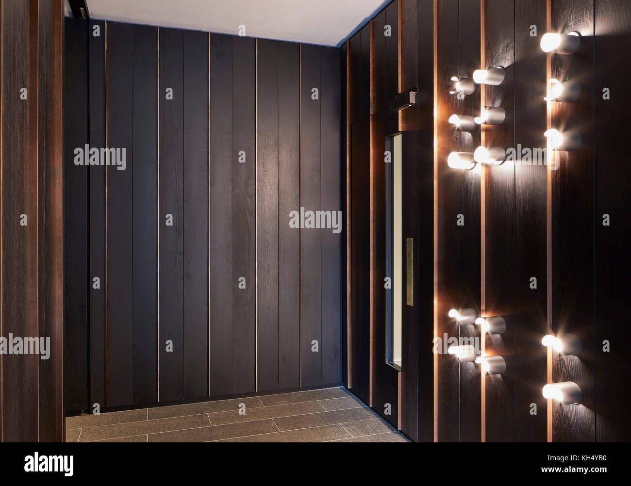 Holztäfelung und Beleuchtungskörper in Gebäude Flur. 55 Victoria Street, London, Vereinigtes Königreich. Architekt: Steif+Trevillion Architekten, 2017. Stockfoto