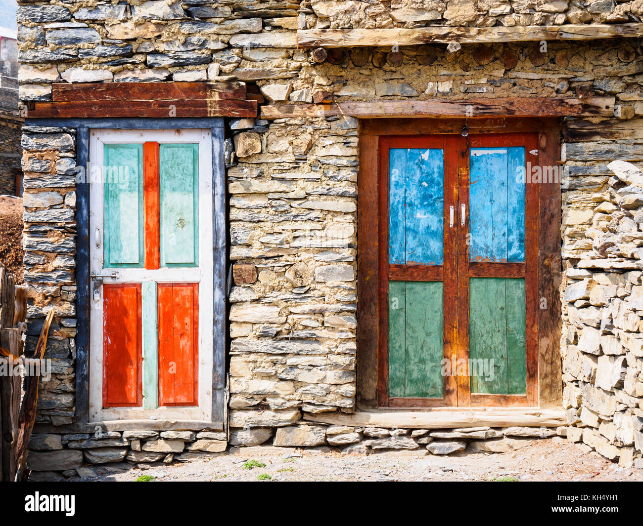 Bunte Holztüren auf braunem Stein Haus in ngawal Dorf, das entlang der berühmten Annapurna Circuit trekking Route in Nepal liegt Stockfoto