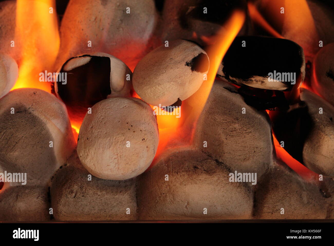 Nahaufnahme der Gasofen Kohlen mit gelb orange Flammen, orange leuchtende und mit Ruß auf zwei der Kohlen. Stockfoto