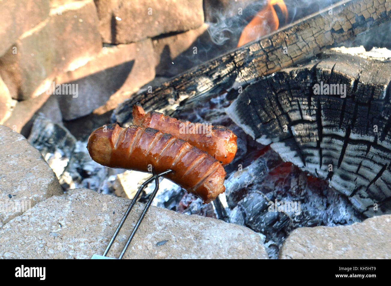 Zwei Jungen sind polnische Würstchen grillen oder Grillen über dem offenen Feuer Grube in ihrem Hinterhof Stockfoto