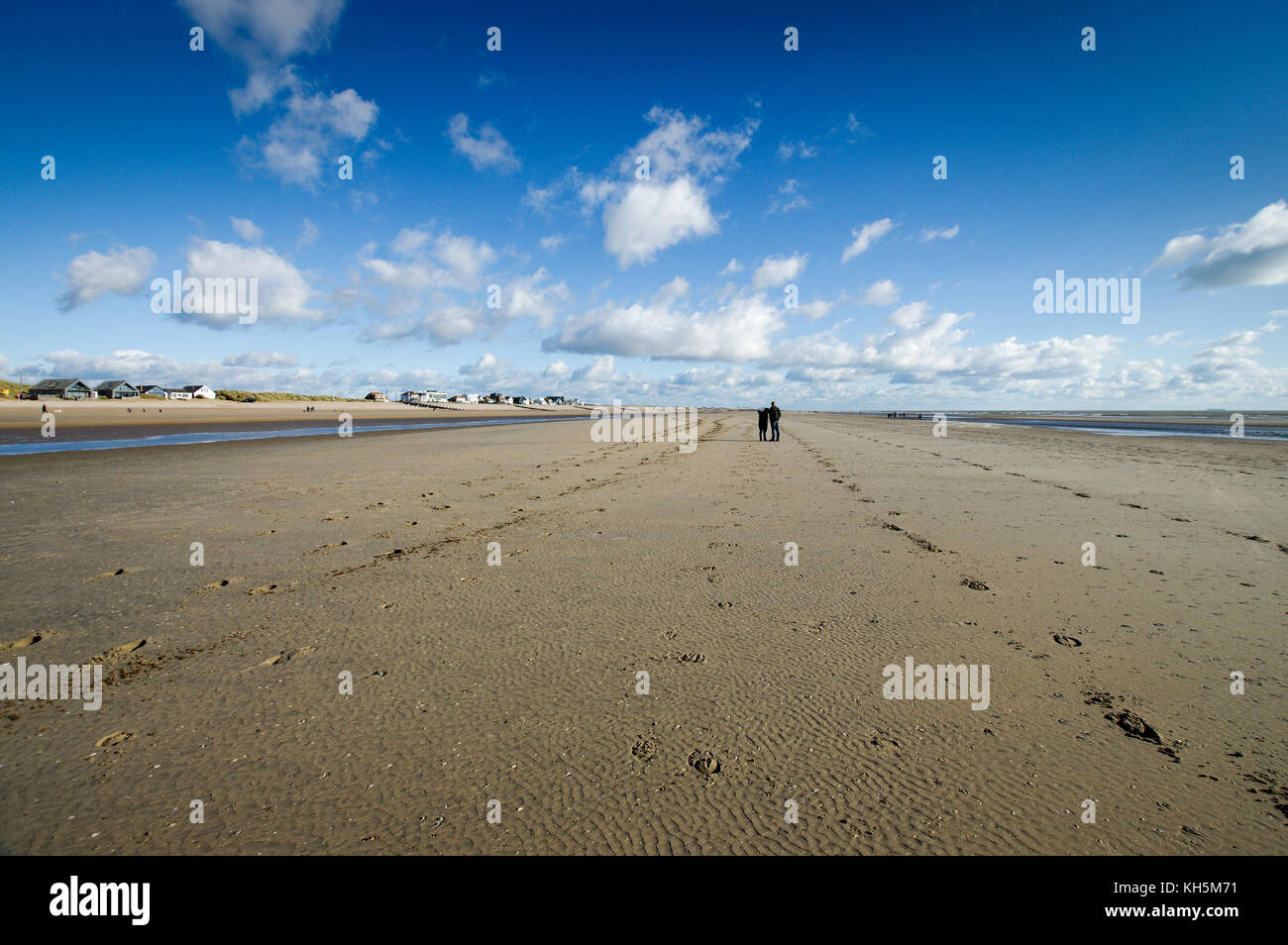 Paar stehend auf Camber Sands Strand bei Ebbe Stockfoto