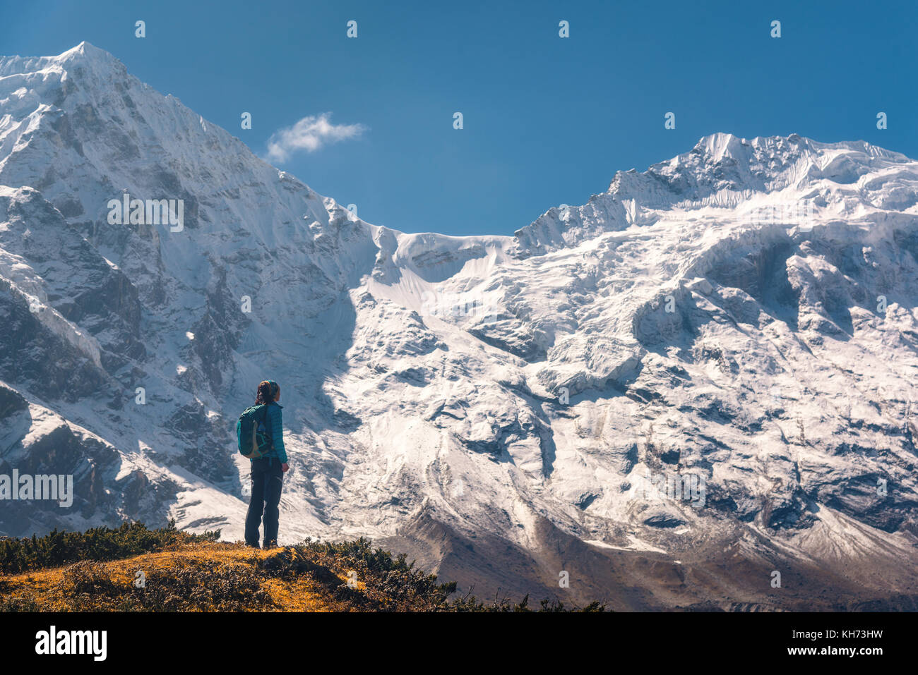 Stehende junge Frau auf dem Hügel und schauen auf erstaunliche Berge des Himalaja. Landschaft mit Reisenden, hohe Felsen mit schneebedeckten Gipfeln, blauer Himmel im Herbst Stockfoto