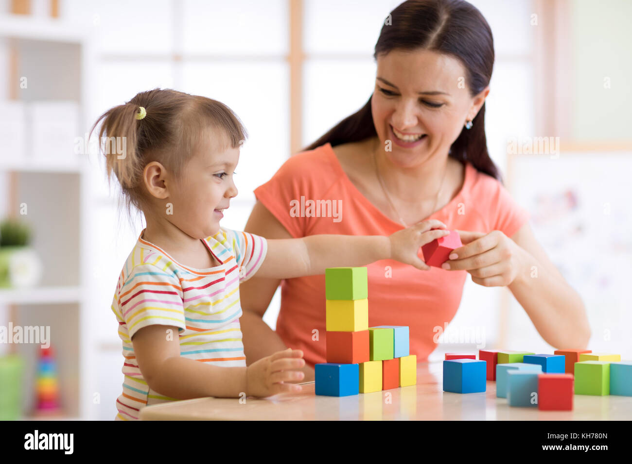 Süße Frau und Kind Mädchen spielen pädagogische Spielwaren im Kindergarten oder Kinderzimmer Stockfoto