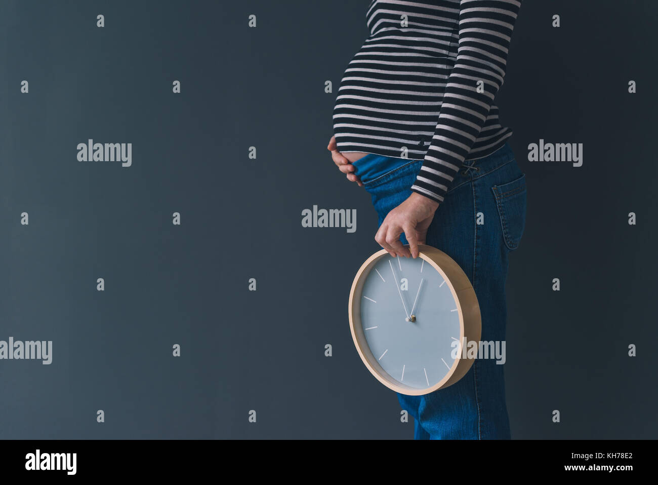 Schwangere mit Vintage Wecker erwartet Baby im dritten Trimenon der Schwangerschaft Stockfoto